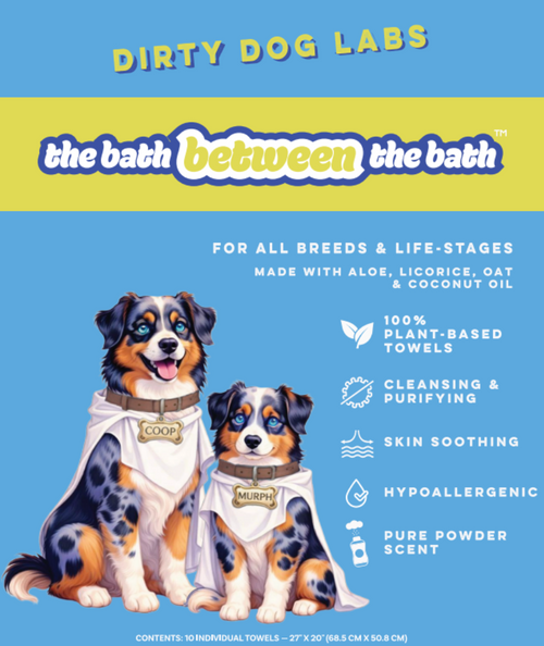Promotional graphic for 'the bath between the bath' by Dirty Dog Labs, featuring two illustrated dogs wearing white towels with brand name tags. The graphic has a light blue background with a yellow banner at the top and text detailing product features like plant-based towels, cleansing, skin soothing, and pure powder scent.